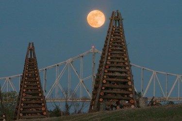 Full moon rising over bonfires and Veterans Memorial Bridge. Louisiana Christmas Eve Bonfires